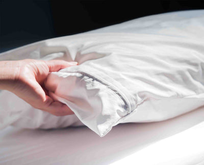 hand pressing a hotel pillow with a T200 pillow protector in white