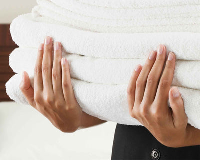 Pile of white bath towel on 2 hands