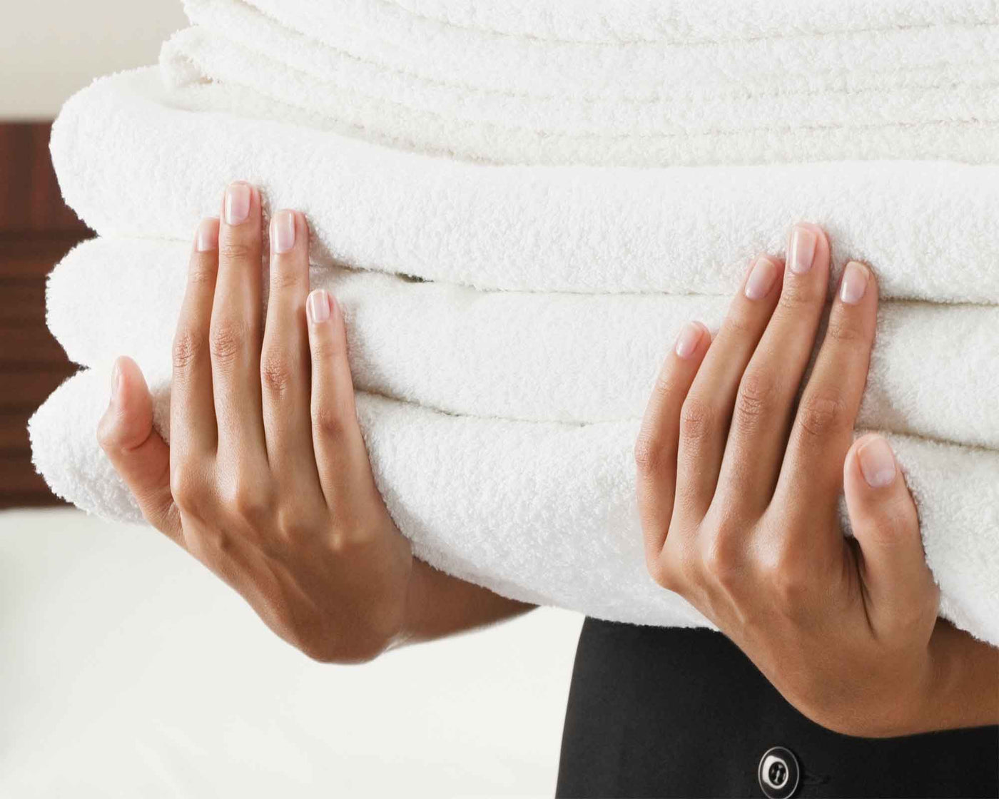 handful of luxury bath towels being carried in a hotel room