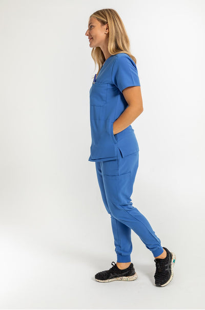 Vena ladies jogger style scrub pants side view image of lady and showing her hand inside the shirt pocket#style_women#colour_royal-blue
