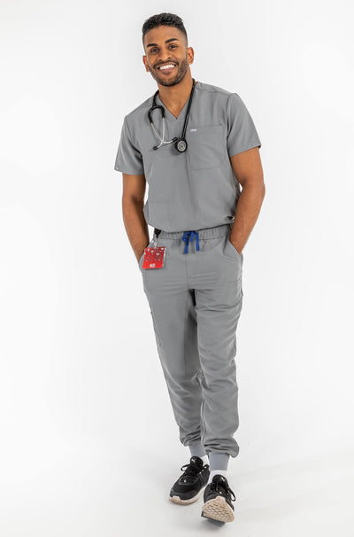 VENA mens jogger style scrub shirts, man standing with his hand in the pocket and with stethoscope on his neck#colour_grey