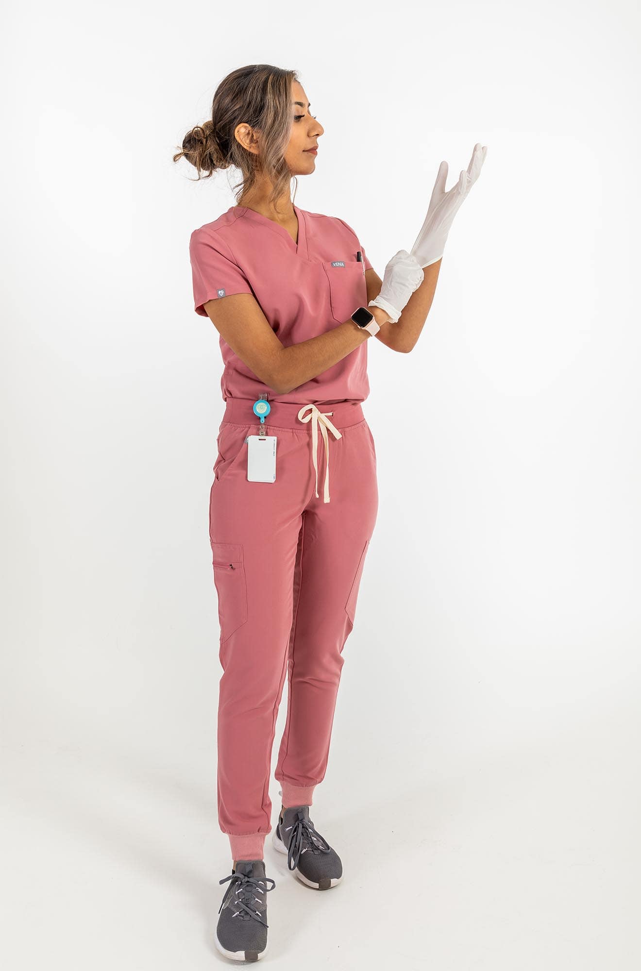 VENA ladies jogger style scrub shirt lady stretching the globes in her hand#colour_rose