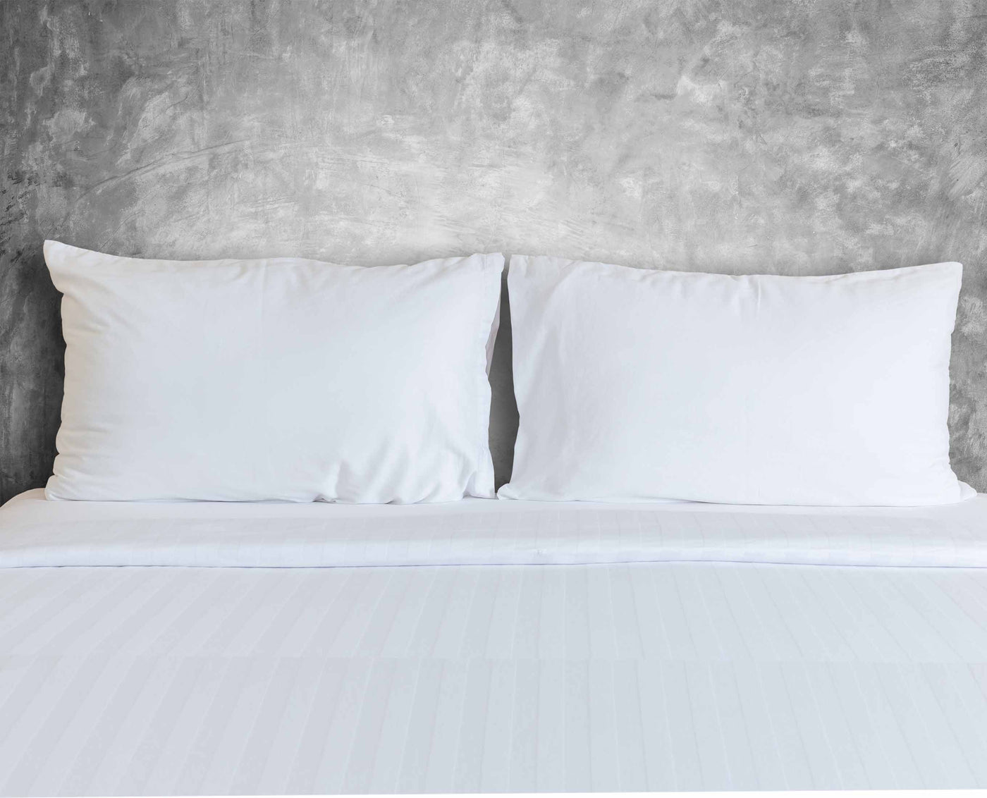 north american made white pillowcases on bed with tone on tone flat sheet